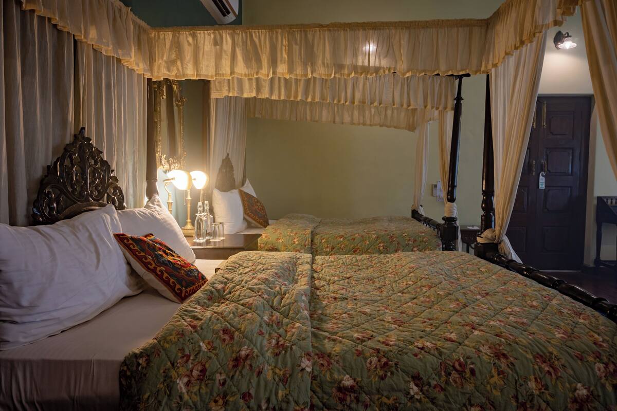 A bedroom with a large bed, a nightstand with a lamp, and a mirror.