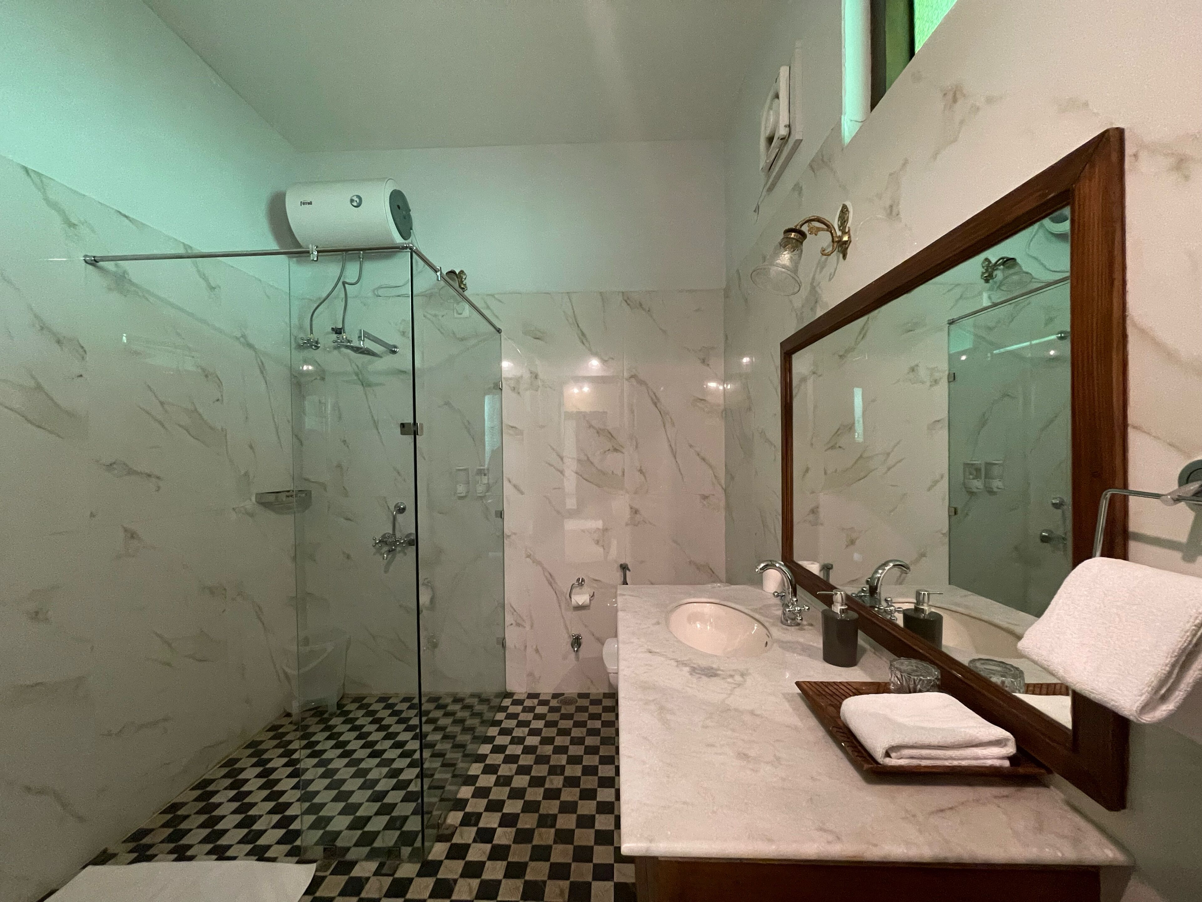 Un baño con cabina de ducha de vidrio, un lavabo con encimera de mármol y un espejo grande.