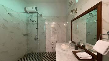 Un baño con cabina de ducha de vidrio, un lavabo con encimera de mármol y un espejo grande.