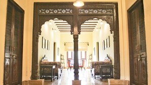 A grand hallway with ornate wooden doors and a central column, leading to a seating area with chairs and a table. - Tree of Life Resort, Dehradun Foothills (Dehradun)