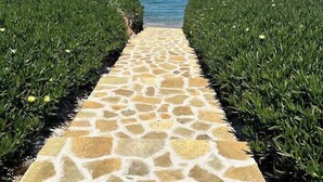 A stone pathway leading to a beach with a clear blue sky.