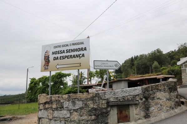 A sign for a social and cultural center with a religious icon, a directional arrow, and a nearby structure.