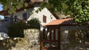 A stone building with a wooden door, a stone wall, and a tiled roof.