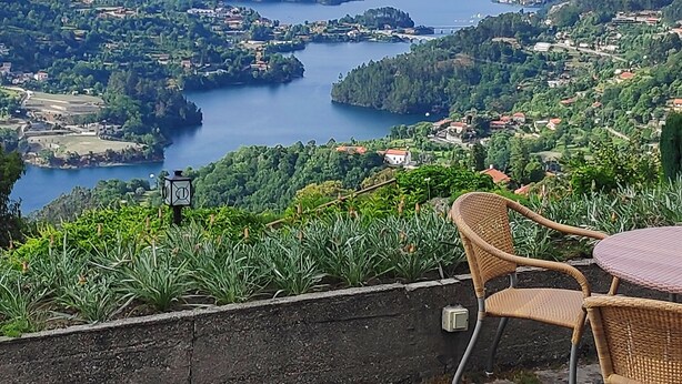 A scenic view of a lake surrounded by mountains, with a chair and table in the foreground.