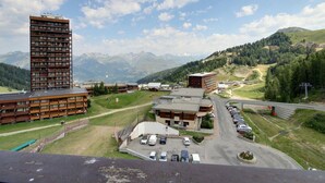 Ein Hotel mit mehreren Etagen, einem Parkplatz und Blick auf Berge im Hintergrund.