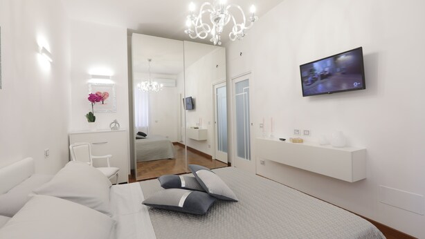 Una camera da letto moderna con un letto, un comodino e una TV a parete.