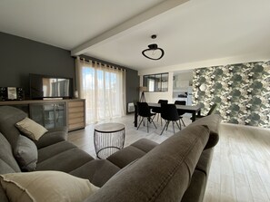 Relax in this stylish living space with a sofa, dining table, and television.