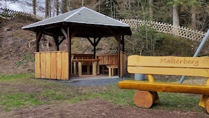 A wooden structure with a bench labeled 'Masserberg' in front. - Ferienwohnung An den Kurwiesen (Masserberg)