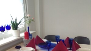 Uma área de refeições com uma mesa posta para quatro, cadeiras e objetos decorativos.