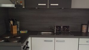 Cozinha moderna com armários escuros, pia de aço inoxidável e painel de azulejos.