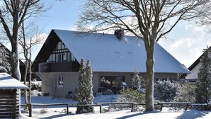 Et snedækket lodge med et stejlt tag, en træhytte til venstre, og en klar himmel.