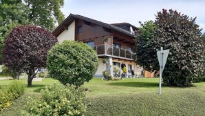 A two-story house with a balcony, surrounded by well-maintained gardens and trees. - Ferienwohnung Fürst (Mauth)
