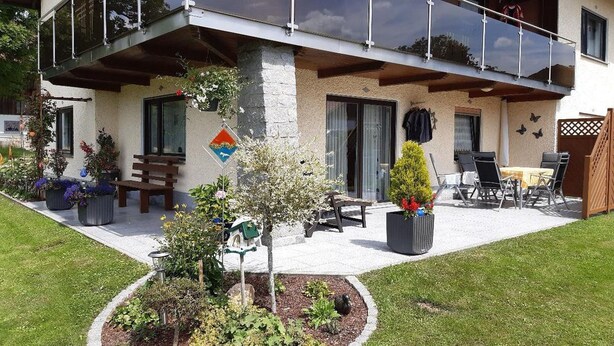 A modern two-story house with a balcony, outdoor seating, and a garden area. - Ferienwohnung Fürst (Mauth)