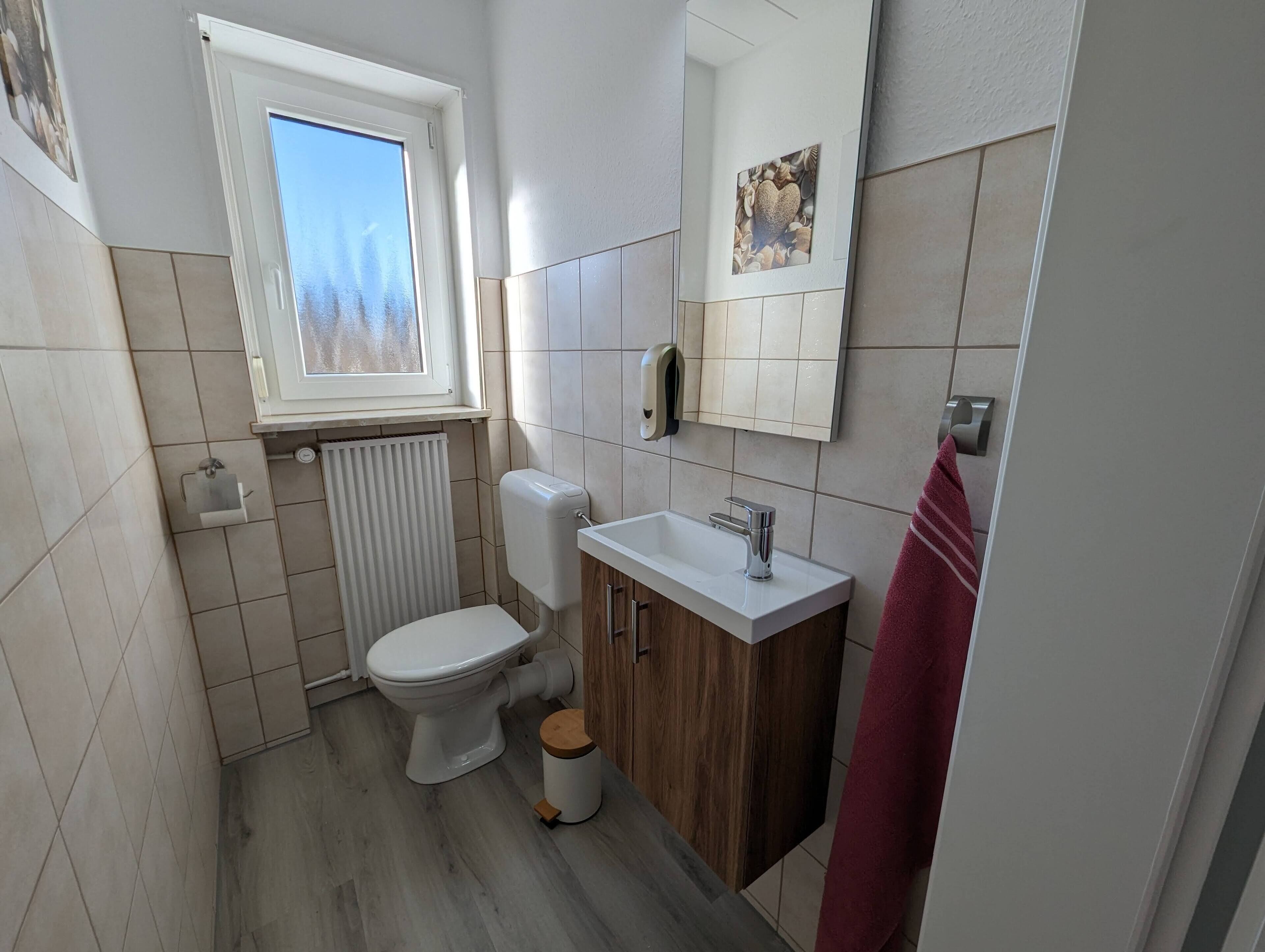 A small, modern bathroom with a toilet, sink, and window.