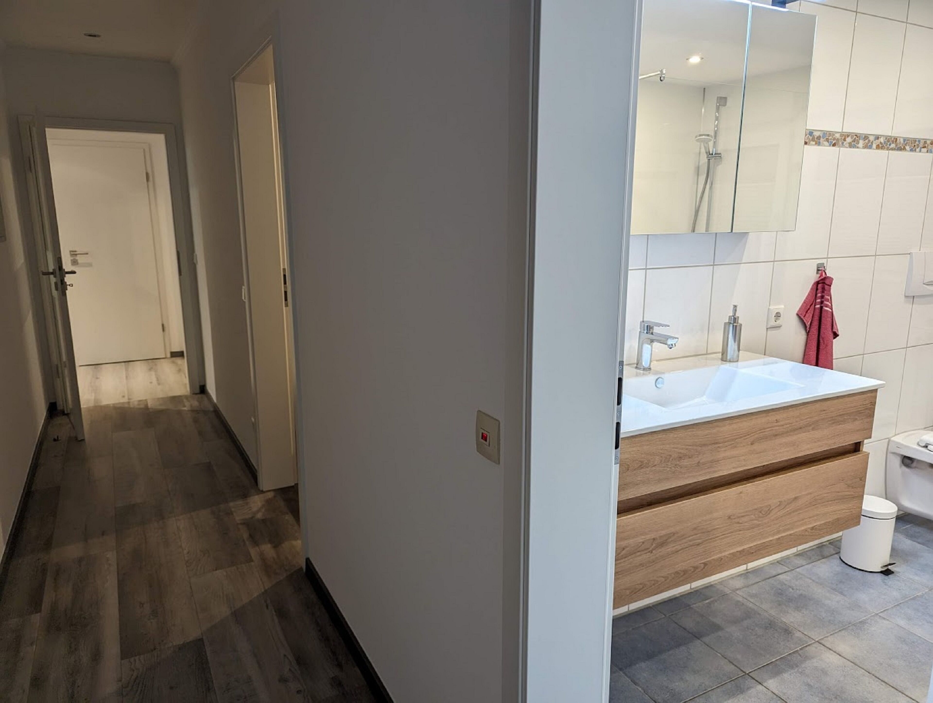 A modern bathroom with a large mirror, a sink, and a toilet.