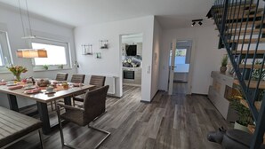 A modern kitchen with a dining area, wooden flooring, and a staircase. - Ferienwohnungen Citylight Winterberg (Winterberg)