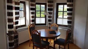 Un coin repas comprenant une table ronde, quatre chaises et un luminaire suspendu.