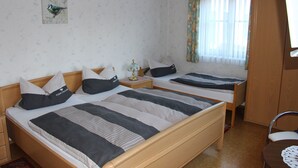 Una habitación con dos camas individuales, un armario de madera, una mesita y una silla.