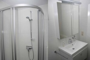 A modern bathroom with a glass-enclosed shower, a white sink, and a mirror above the vanity.