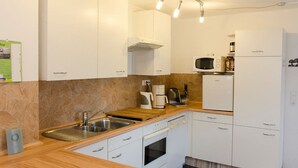 Una cocina compacta con armarios blancos, microondas, cafetera y lavavajillas.