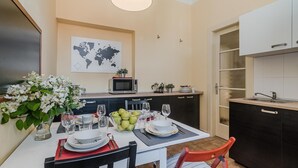A compact kitchen with a dining area set for four. There's a world map on the wall, a microwave, and a small coffee maker on the counter. - APT in Center Prague by Michal&Friends (Prague)