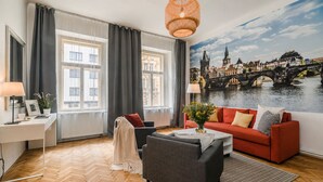 A room with a red sofa, a grey armchair, a white desk, and a large window with curtains. - APT in Center Prague by Michal&Friends (Prague)