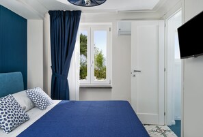 Quarto com cama, cortinas, janela e televisão.