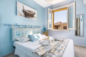 Quarto com cama, janela, quadro na parede e planta em vaso.
