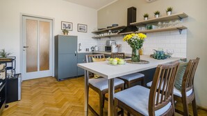 Una cucina moderna con zona pranzo, caratterizzata da un pavimento a spina di pesce, un'isola centrale con un vaso di fiori e un forno integrato.