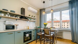Una cucina compatta con forno a microonde, tostapane e forno, una zona pranzo con sedie di legno e una finestra con vista sulla città.