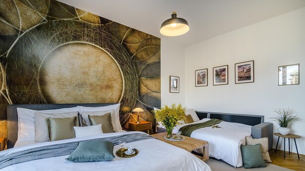Una camera d'hotel con due letti, un grande murale astratto sulla parete, un tavolino con un vaso e quadri appesi alla parete.