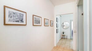 Un corridoio con quadri appesi al muro, un tavolino con una pianta e uno specchio.