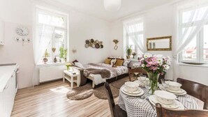 A bright, well-lit room with a bed, a dining table set for two, and a large window with sheer curtains. - APT in Alb. nad Orlici by Michal&Friends (Albrechtice nad Orlicí)