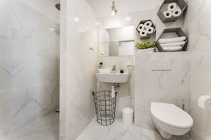 A modern bathroom with white marble tiles, a white sink, a toilet, and a shower area. - APT in Alb. nad Orlici by Michal&Friends (Albrechtice nad Orlicí)