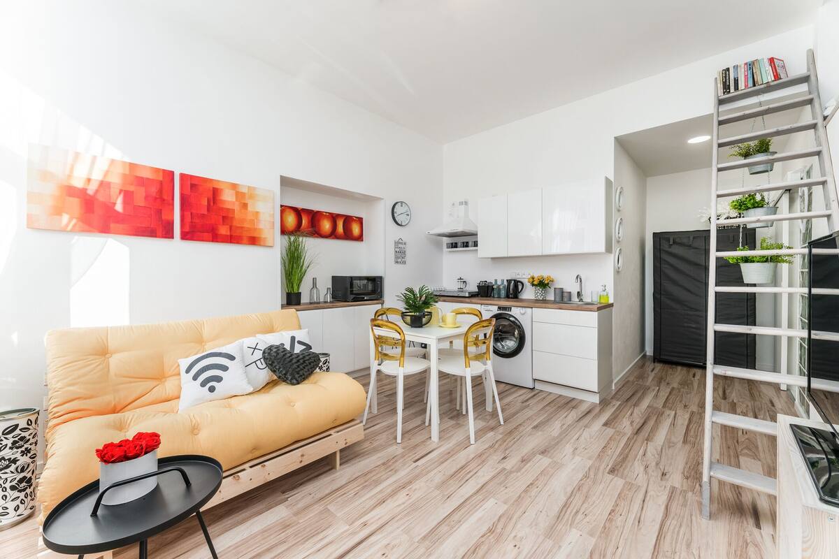 Ett kompakt bostadsutrymme med en soffa, ett matbord och ett köksområde.