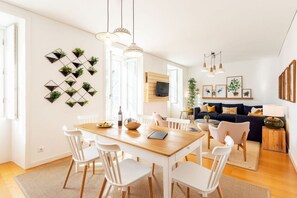 Un espacio habitable moderno con comedor, sofá y televisor montado en la pared.