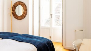A bedroom with a bed, a mirror, and a door leading to a balcony. - JOIVY Chiado Self Check-In 2-BR Flat w/Parking (Lisbon)