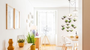 A bright, modern dining area with a wooden table, white chairs, and a fan. There are potted plants and a wall-mounted light fixture. - JOIVY Chiado Self Check-In 2-BR Flat w/Parking (Lisbon)