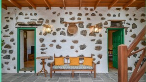 A stone-walled room with a wooden bench, two doors, and a small table. - Rustic Holiday Home "Casa Rural Tamia" with Terrace and Mountain View, Wi-Fi (Tao)