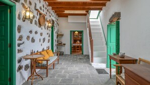 A stone-floored interior with wooden furniture, green doors, and a staircase leading to an upper level. - Rustic Holiday Home "Casa Rural Tamia" with Terrace and Mountain View, Wi-Fi (Tao)