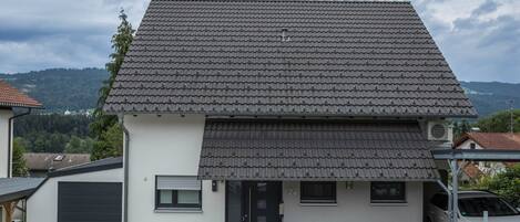 A two-story house with a tiled roof, a garage, and a car parked in the driveway.