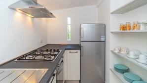 A modern kitchen with a gas stove, stainless steel refrigerator, and white cabinetry. - Holiday Home "Appartamento del Cormorano" Near the Beach and with & Air Conditioning (OLBIA)