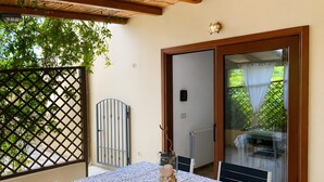 Un balcon avec une table dressée pour deux personnes, une véranda et une vue sur la verdure.
