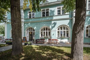 A building with the sign "GASTWIRTSCHAFT" indicating it is a guesthouse. There are benches outside and a paved walkway.