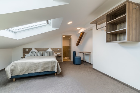 A modern bedroom with a skylight, a bed, a bedside table, and a built-in wooden shelf.