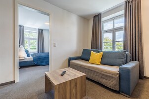 Una habitación moderna con un sofá, una mesita de madera y una ventana con cortinas.