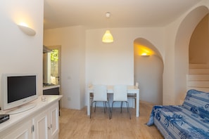 A modern room with a TV, a dining table with chairs, a patterned sofa, and a pendant light. - Modern Holiday Home "Villa Rosa dei Venti" Near the Beach and with Sea View (OLBIA)