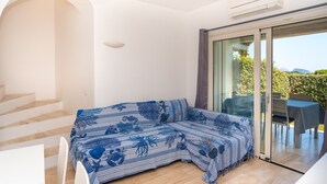 Una habitación moderna con un sofá, una escalera y un ventanal corredera que da a un espacio exterior.