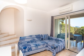 Ein modernes Zimmer mit einer Couch, einer Treppe und einer Glasschiebetür, die zu einem Außenbereich führt.