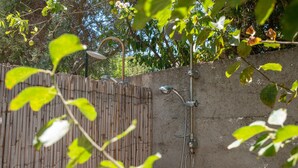 Ducha de concreto con cerramiento de bambú, grifo metálico y ducha de mano.